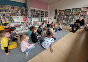 Dzieci siedzą na dywanie i słuchają wierszy M. Konopnickiej czytanych przez p. Włodzimierza Adamskiego